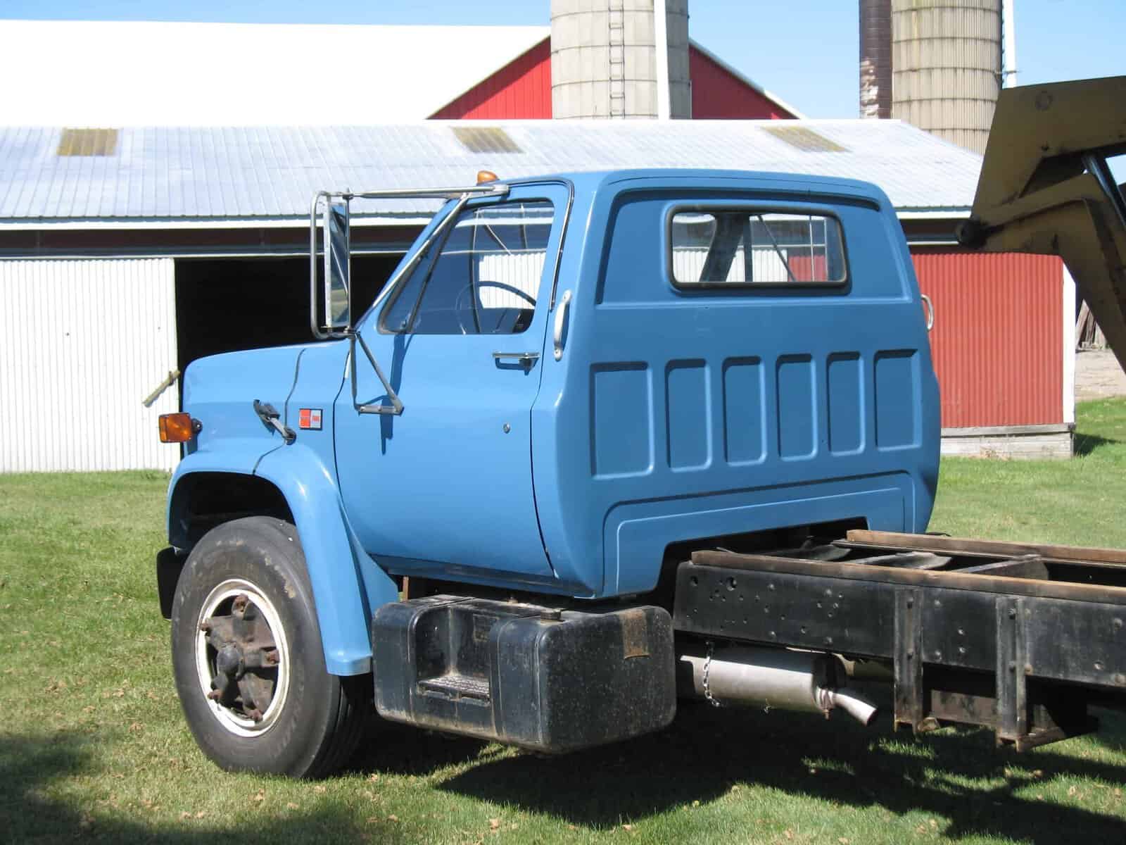 1985 GMC C7000 Cab Image 1985 GMC C7000 cab with blue paint and single cab, viewed from rear-left on a grassy lot.
