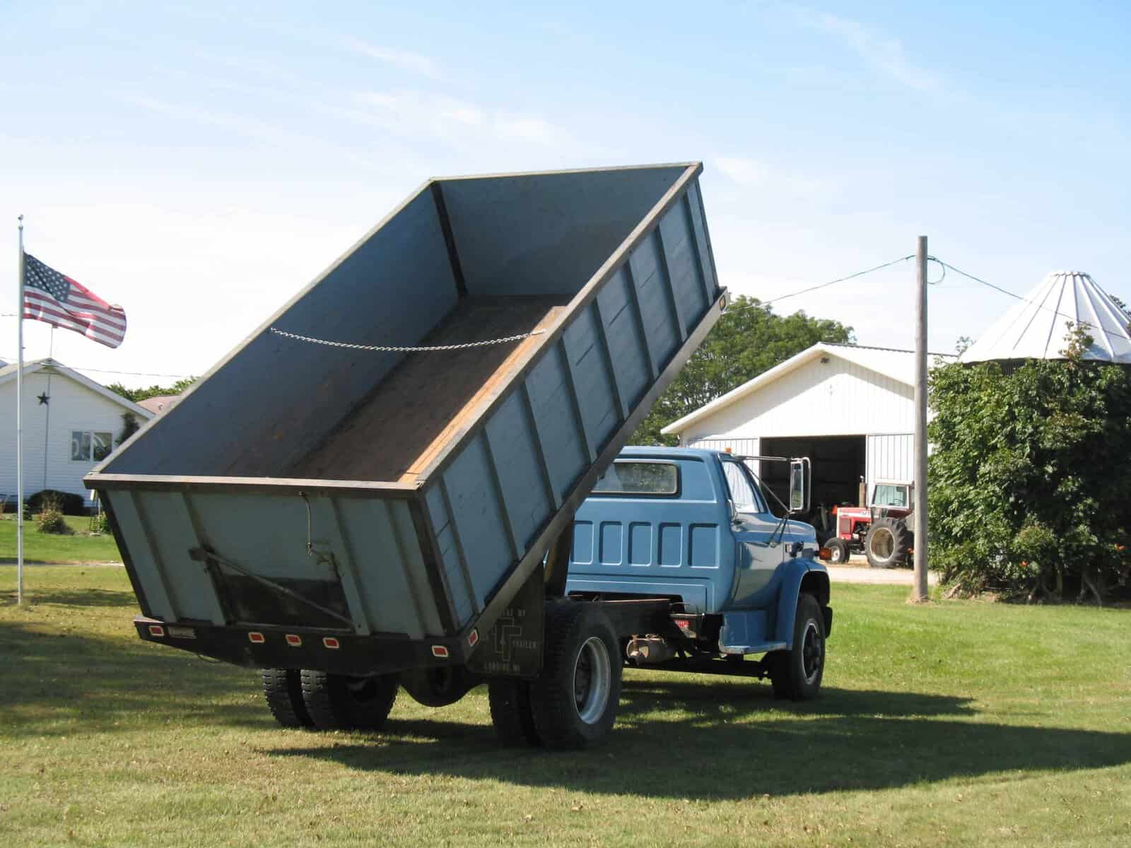 1985 GMC C7000 Dump Truck Lifted Bed 1985 GMC C7000 dump truck with raised dump bed on a grassy lot.