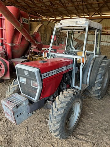 1997 Massey Ferguson 394S tractor with cab, front weights, and dual rear tires in a barn setting.