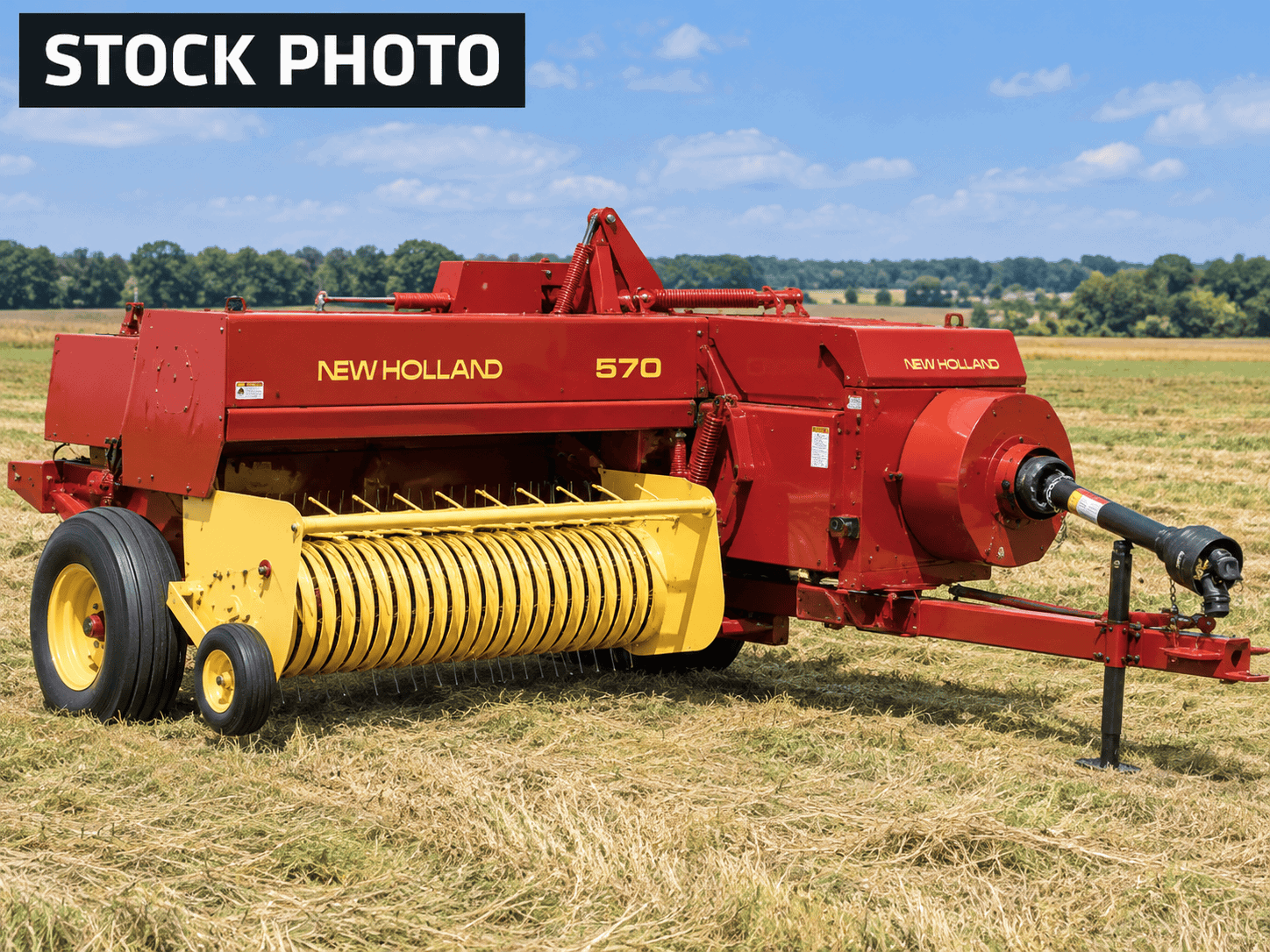 New Holland 570 Baler in Rural Field (1) New Holland 570 hay rake with yellow tines and red body in a field.