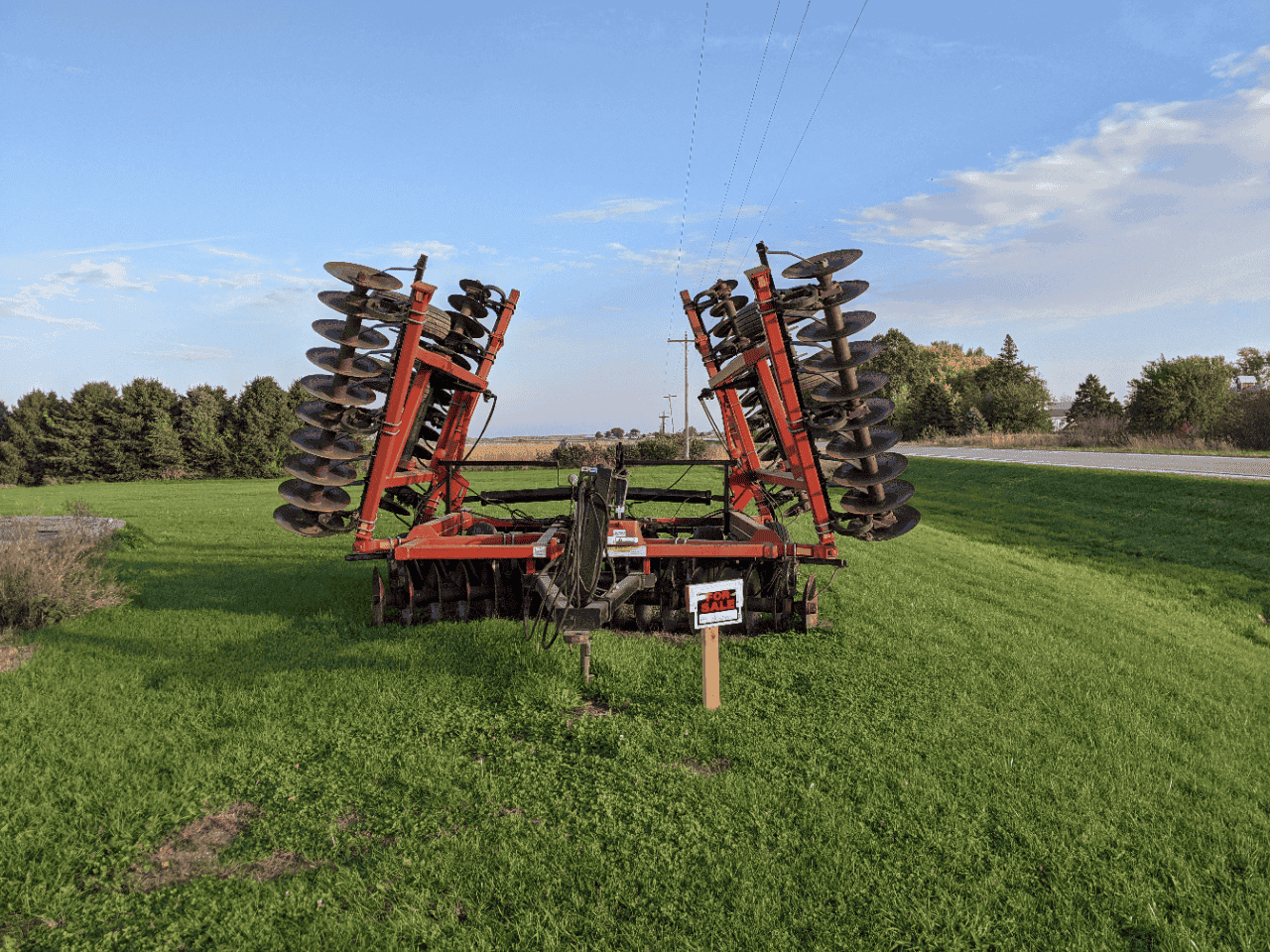 Versatile TD500 Field Cultivator Attachment Versatile TD500 field cultivator with multiple large disc blades and red frame in a grassy lot.