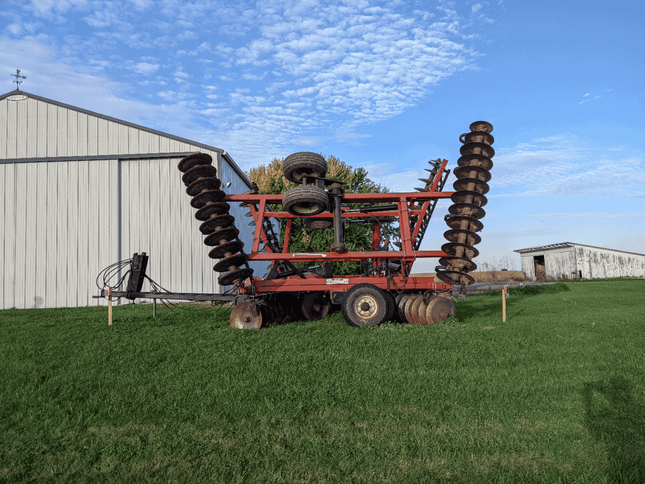 Versatile TD500 Disc Harrow Attachment TD500 disc harrow attachment with dual spring coil wings and tires on a red frame in a field.