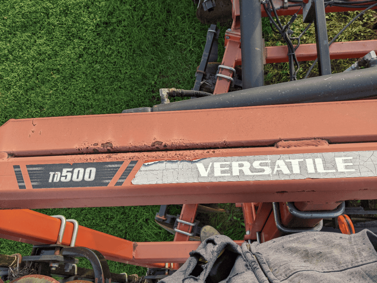 Versatile TD500 Equipment Harvester TD500 Versatile machinery with orange frame and attachment shows worn paint.