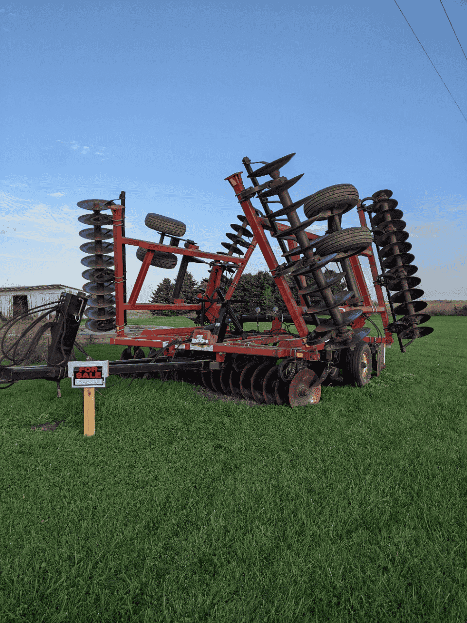 Versatile TD500 Disk Harrow Assembly TD500 disk harrow mounted on red frame with multiple discs and hubs in a field.