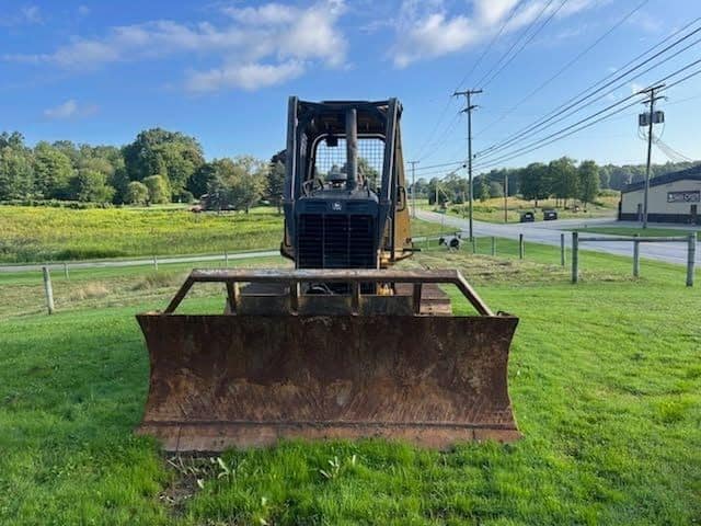 RAW_JD 650H 2 John Deere 650H bulldozer with large blade on grassy field under blue sky.