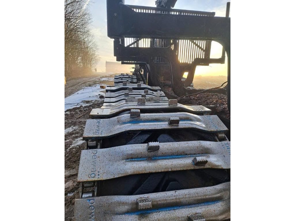 RAW_Logset 5 Close-up of tracked forestry equipment with visible metal tracks and undercarriage at sunset.