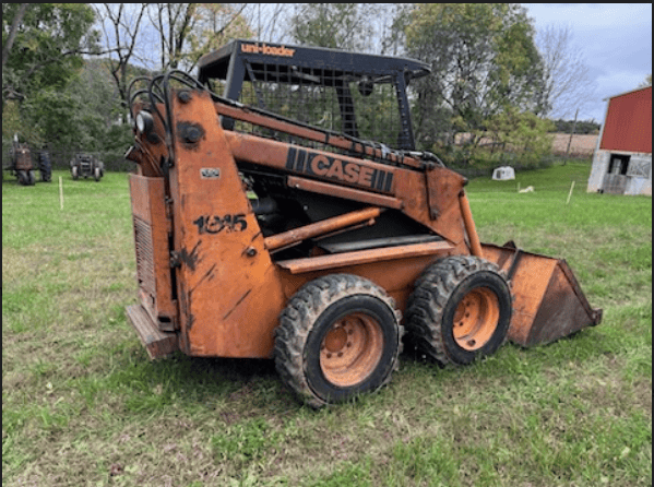 Case 1845 Skid Steer Loader for Sale Orange Case 1845 skid steer loader with bucket attachment on grassy field.