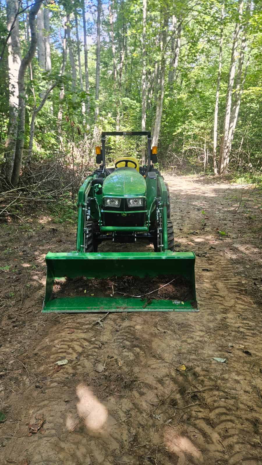 image000000 (10) 2021 John Deere 3025E compact tractor with front loader in wooded area.