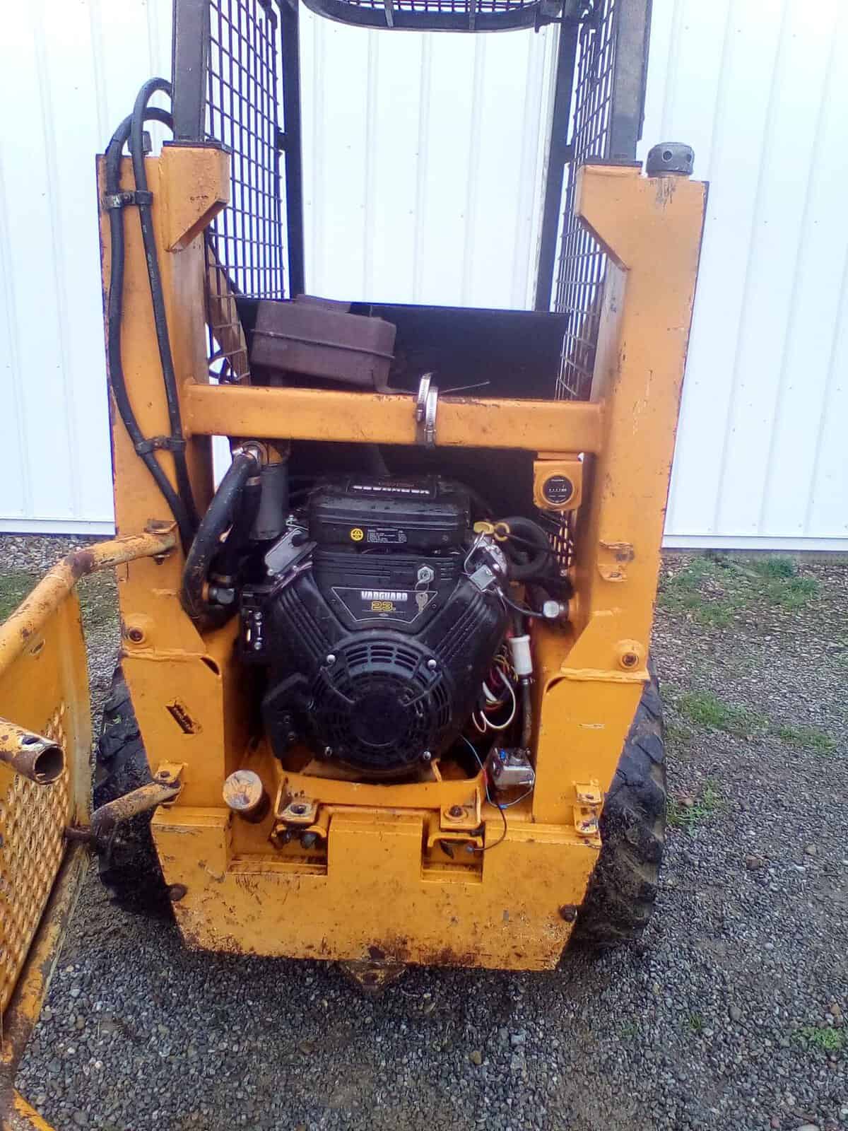 image000001 (11) Yellow skid steer loader with open engine compartment and protective cage.