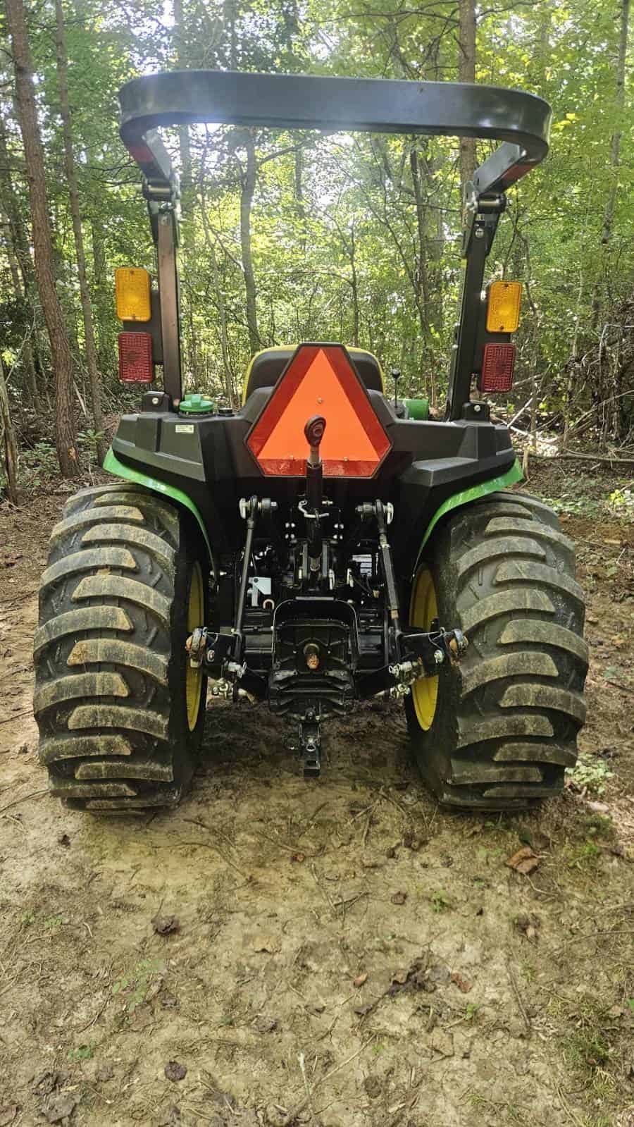 image000001 (9) 2021 John Deere 3025E compact utility tractor with ROPS and rear hitch in wooded area.