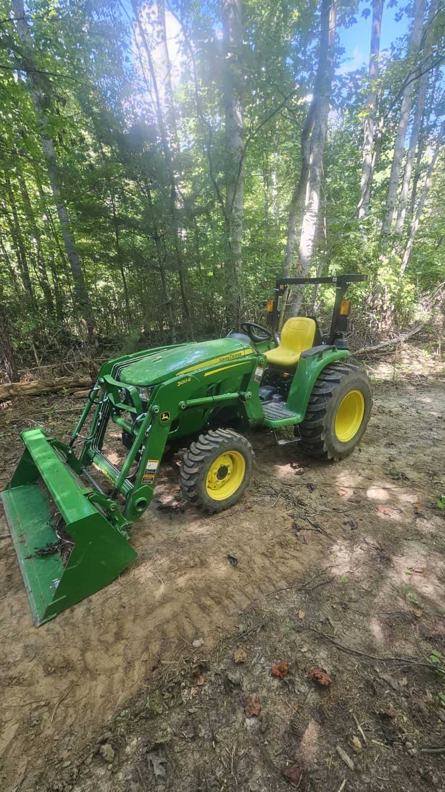 image000002 (9) 2021 John Deere 3025E compact tractor with front loader and yellow seat in wooded area.