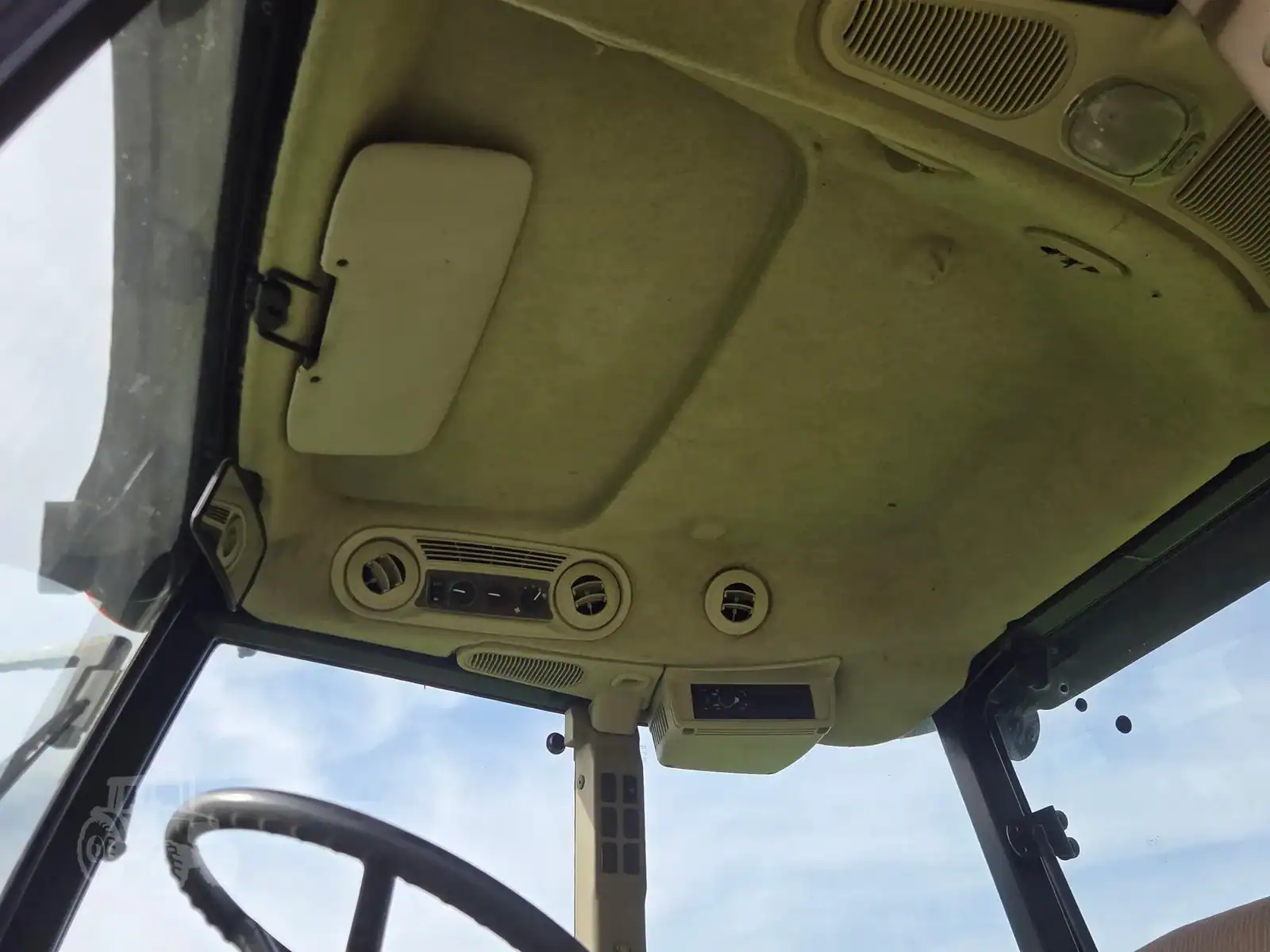 img (15) Interior view of a 2010 John Deere 5101E tractor cab with control panel and steering wheel.