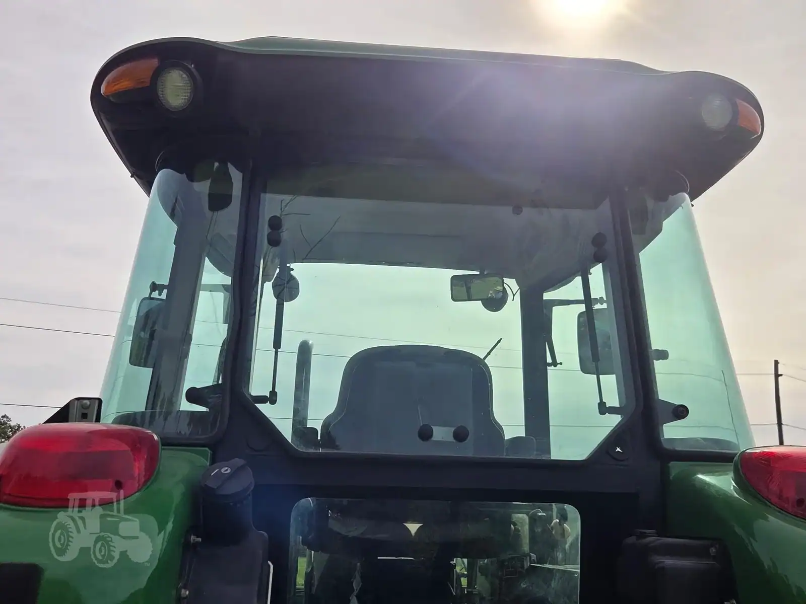 img (7) Green John Deere tractor with enclosed cab and large windshield, front view.