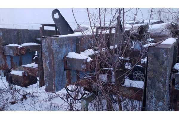 Old, rusty farm equipment and machinery in a snowy outdoor setting.