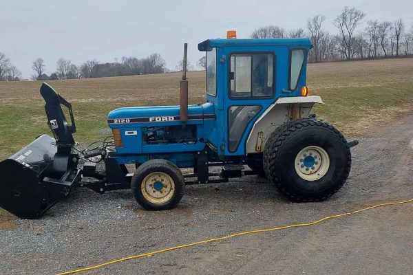 Ford 2120 tractor with front loader attachment on a gravel surface.