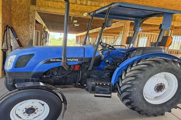 2004 New Holland TN70 blue tractor with cab and large rear tires.