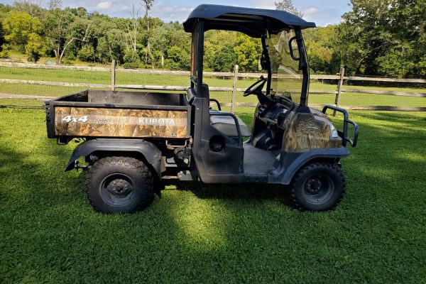 Kubota RTV900 4x4 utility vehicle with cargo bed and canopy, outdoor setting.