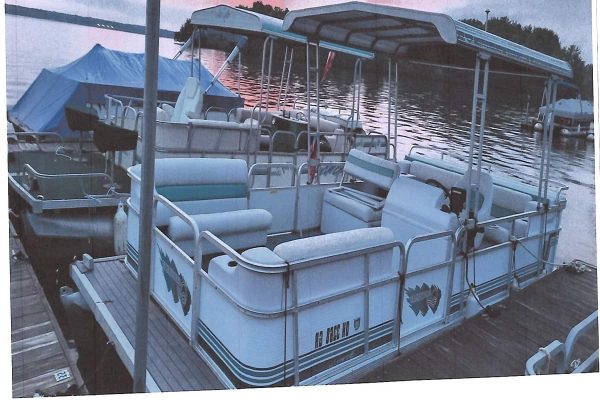 Suncruiser pontoon boat with canopy, seating, and safety rails on dock at sunset.