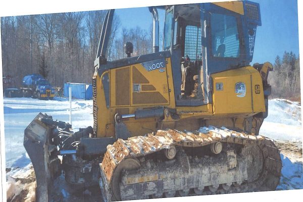 Yellow John Deere 850K crawler dozer with blade in snowy landscape, cab, and tracks.