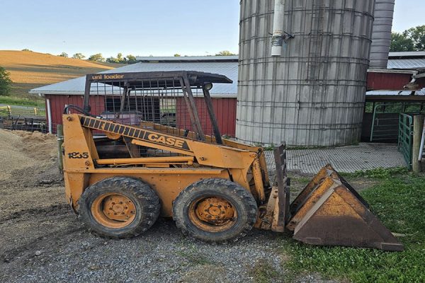 Case 1835 skid steer loader with bucket attachment on farm ground.
