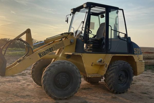 2000 Kramer-Allrad 520 compact loader with cab and front bucket at sunset.