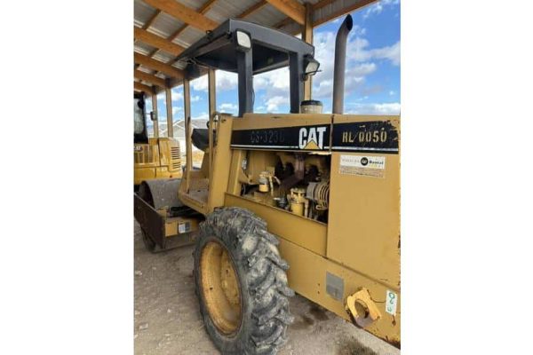 CAT HL0050 compact wheel loader from 2021 under a wooden shelter with blue sky background.