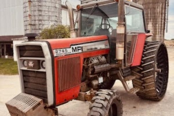 Massey Ferguson 2745 tractor with cab and large rear tires, parked near silos.