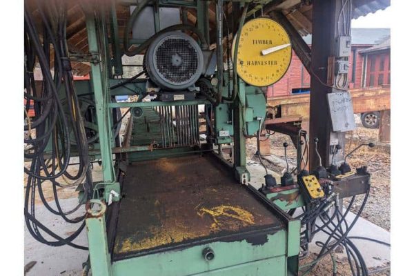 Heavy-duty green logging sawmill with control panel and hydraulic system for timber processing.