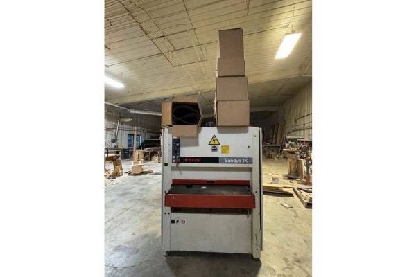 Sandya TSK industrial paper cutting machine in a warehouse setting, with stacked cardboard on top.