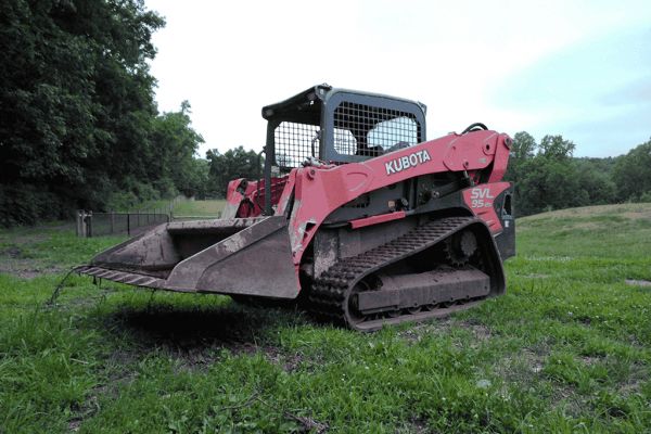 2018 Kubota SVL95-2 compact track loader with enclosed cab and bucket attachment on grassy field.