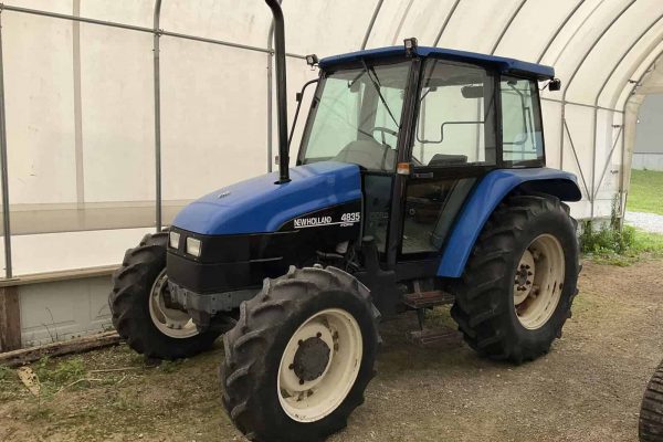 New Holland 4635 tractor with enclosed cab and large rear tires.