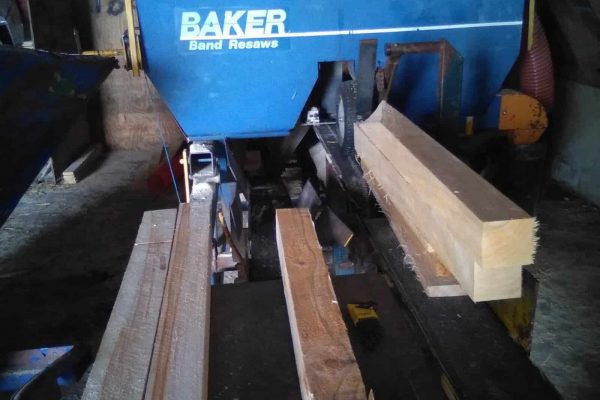 Heavy-duty wood cutting saw with blue Baker Band Resaws machine in a workshop.
