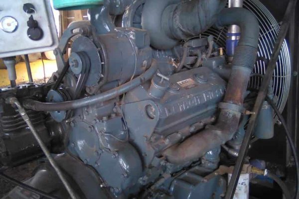 Industrial diesel engine with various hoses and components in a workshop setting.