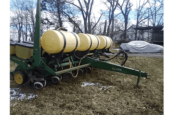 A tractor-mounted liquid fertilizer spreader with yellow tanks, green frame, and John Deere branding, set outdoors on a grass.
