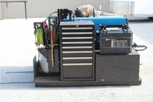 Portable industrial generator with blue and black casing, equipped with tools and control panel.