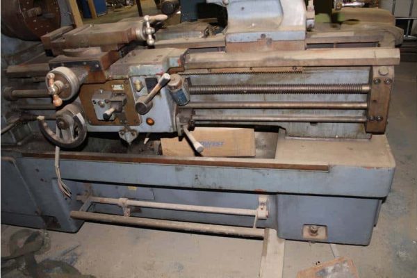 Heavy industrial metal lathe machine with rust and wear, used for precision machining tasks.