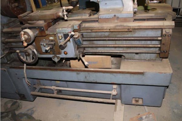 Heavy industrial metal lathe machine with rust and wear, used for precision machining tasks.