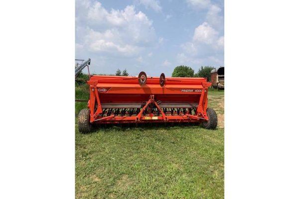 Red 2020 John Deere rotary tiller attachment for tractors, outdoor equipment, on grassy field under blue sky.