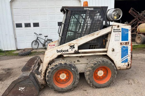Compact Bobcat skid-steer loader with bucket attachment, white and black, 2010 model, suitable for construction and landscapi.