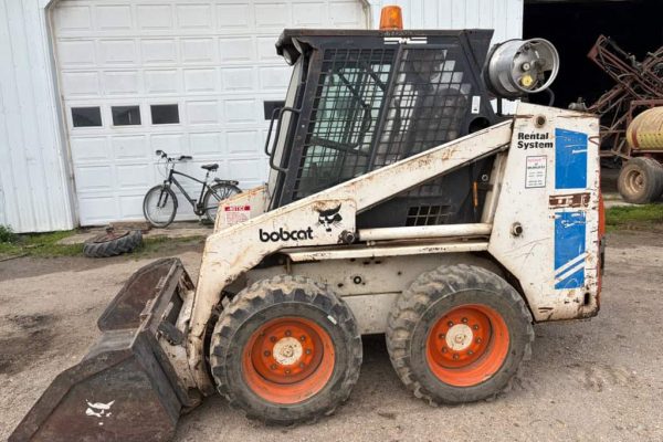 Compact Bobcat skid-steer loader with bucket attachment, white and black, 2010 model, suitable for construction and landscapi.
