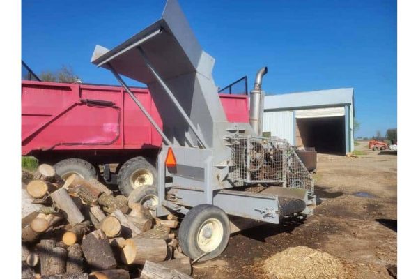 A wood chipper machine with a large hopper and wheels, used for processing logs into mulch.