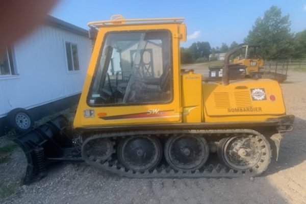 Yellow Bomag BW80AD-4 compact track loader with cab and rubber tracks on gravel surface.