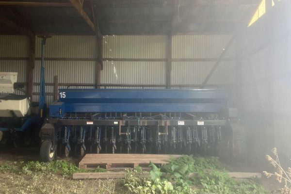 2015 blue agricultural seeder with multiple seed dispensers in a barn.