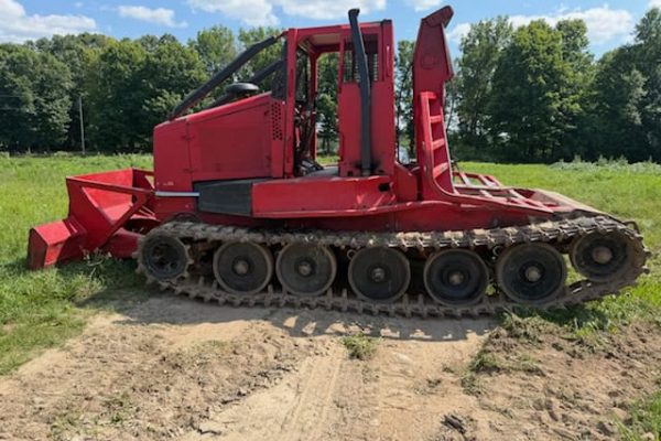 KMC 1000AG track skidder with red body and rubber tracks on grassy field.