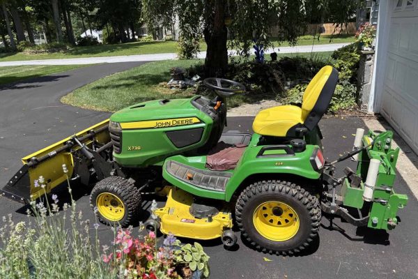 John Deere X730 lawn tractor with front mower deck and snowblower attachment in driveway.