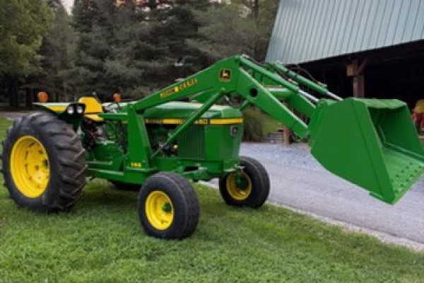 Green John Deere 2440 compact tractor with front loader and yellow wheels on grassy area.