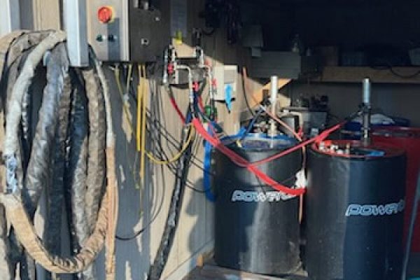 Electrical control panel with hoses and tanks for spray foam insulation system.