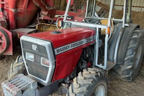 1997 Massey Ferguson 394S tractor with cab, front weights, and dual rear tires in a barn setting.