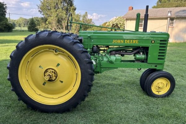 Vintage 1947 John Deere B tractor with green body and yellow wheels on grassy field.