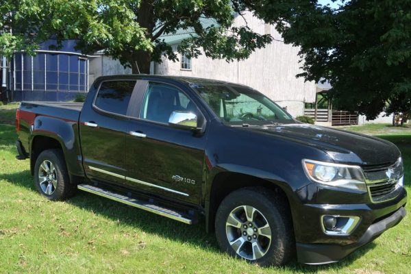 2018 Chevrolet Colorado Z71 black pickup truck parked on grass with trees.
